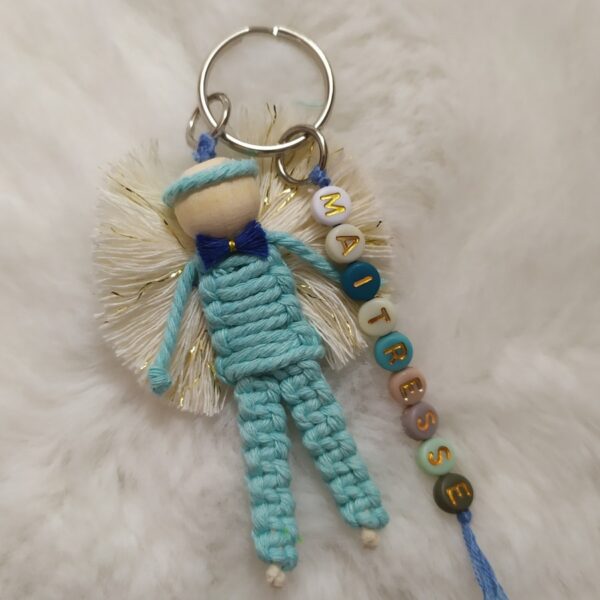 Ange gardien réalisé en corde de macramé de coton bleu clair, monté sur porte clés en metal argenté. Personnalisé avec le mot maitresse en perles acryliques